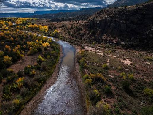 Aerial view of the winding Canadian River surrounded by fall-colored trees and red-rock canyons
